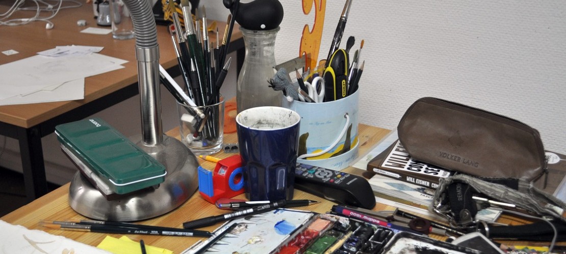 Auf dem Schreibtisch eines Illustrators findet man Farben, Pinsel und Stifte. (Foto: dpa)