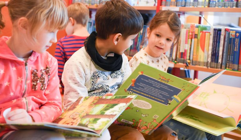 Kinder schauen sich Bücher an. (Foto: dpa)