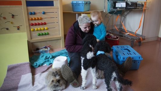 Die 43-jährige Tiertherapeutin Bianca Terhürne sitzt in der Dortmunder Kinderklinik mit der zweijährigen Maria Ost neben ihren Hunden und Kaninchen. (Foto: dpa)